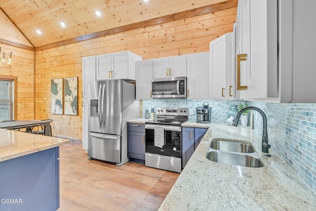 kitchen featuring stainless steel appliances, lofted ceiling, a sink, and light stone counters