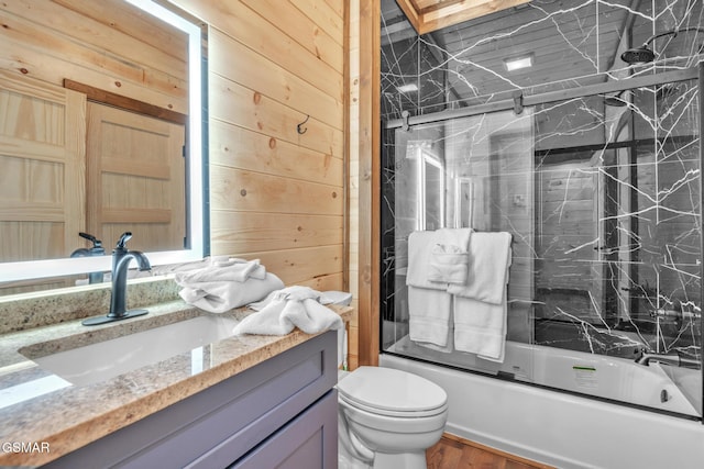 bathroom featuring enclosed tub / shower combo, toilet, wood walls, wood finished floors, and vanity