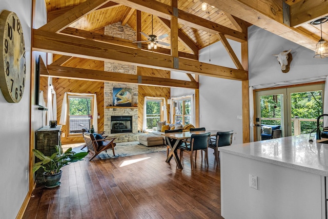 dining room featuring ceiling fan, sink, a stone fireplace, hardwood / wood-style floors, and wooden walls