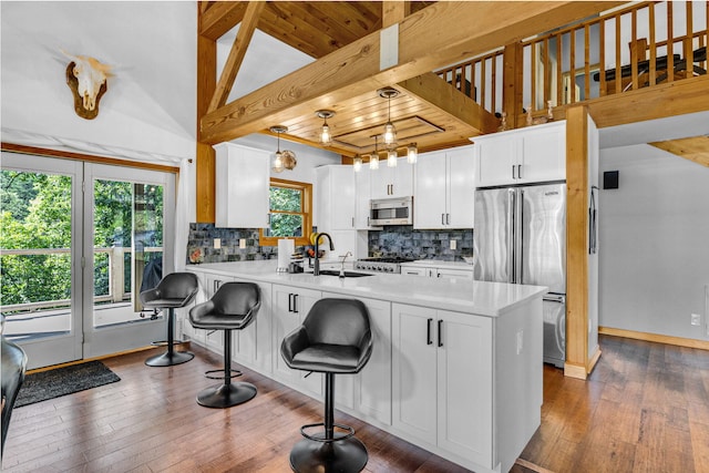 kitchen featuring kitchen peninsula, appliances with stainless steel finishes, tasteful backsplash, and white cabinetry