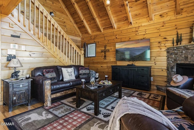 living room with hardwood / wood-style flooring, stairway, wood ceiling, wood walls, and a stone fireplace