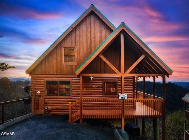 view of front of house with board and batten siding, a deck, and log siding