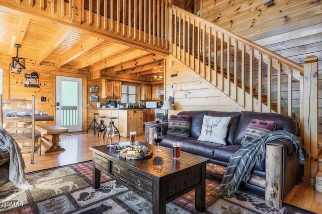 living area with wooden walls, wood finished floors, beamed ceiling, stairs, and wood ceiling