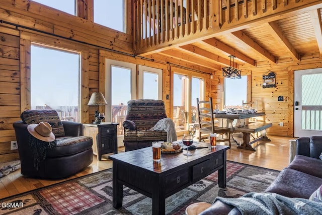 living area featuring plenty of natural light, beamed ceiling, wood-type flooring, wooden walls, and wood ceiling