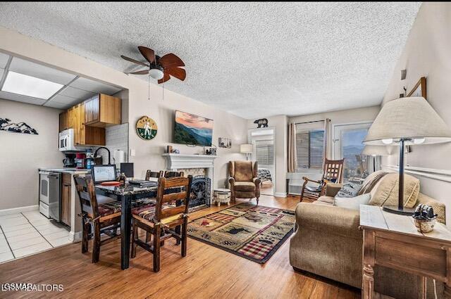 102 Baskins Creek Byp Unit 104, Gatlinburg, TN 37738 - dining area featuring a ceiling fan, a fireplace, a textured ceiling, light wood-type flooring, and baseboards