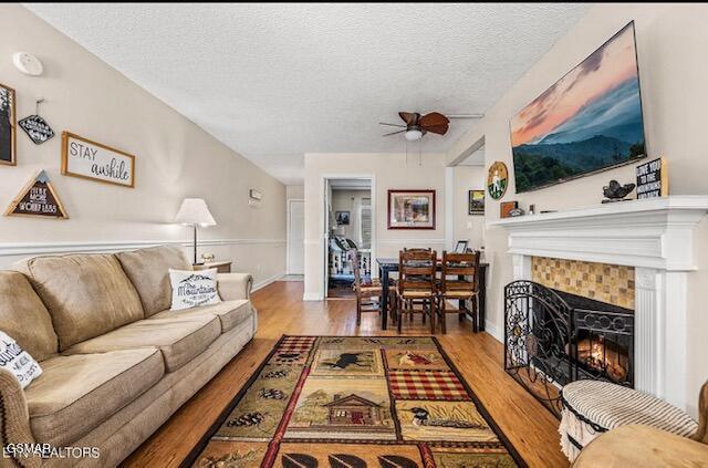 102 Baskins Creek Byp Unit 104, Gatlinburg, TN 37738 - living room featuring ceiling fan, wood finished floors, a textured ceiling, a tiled fireplace, and baseboards