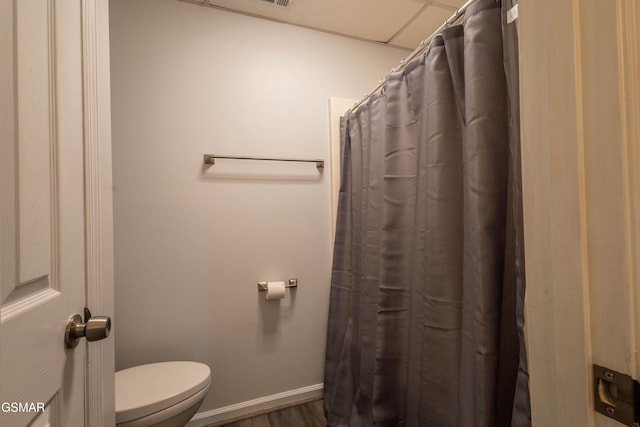 bathroom with hardwood / wood-style floors, a drop ceiling, and toilet