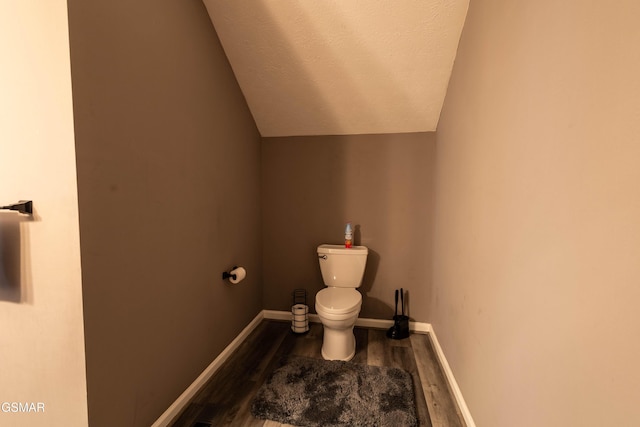 bathroom with hardwood / wood-style flooring, vaulted ceiling, a textured ceiling, and toilet