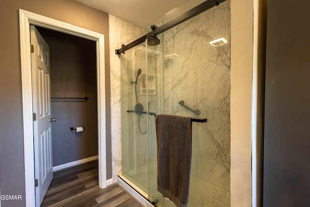 bathroom with hardwood / wood-style flooring, a textured ceiling, and a shower with shower door