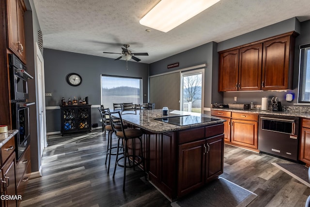 kitchen with a center island, dark stone countertops, a kitchen breakfast bar, and dark wood-type flooring