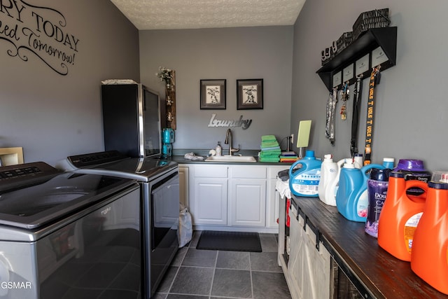 laundry room with washer and dryer, sink, dark tile patterned flooring, cabinets, and a textured ceiling