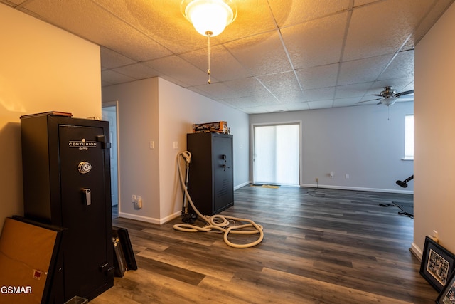 interior space with dark wood-type flooring, a drop ceiling, and ceiling fan