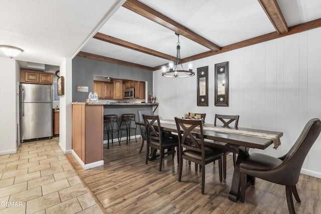 dining area with a notable chandelier, beam ceiling, and light wood-type flooring