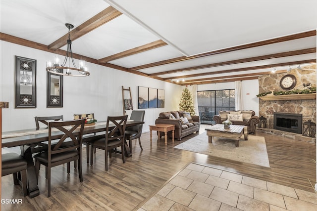 dining room with a fireplace, hardwood / wood-style floors, an inviting chandelier, and beamed ceiling