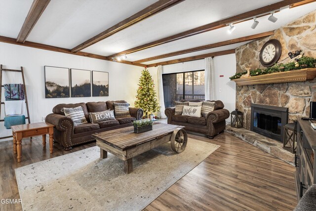 living room featuring rail lighting, beam ceiling, dark hardwood / wood-style flooring, and a fireplace