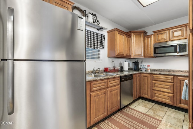 kitchen featuring light tile patterned flooring, appliances with stainless steel finishes, dark stone counters, and sink