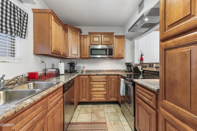 kitchen with stone counters, appliances with stainless steel finishes, wall chimney exhaust hood, and sink