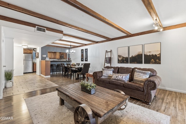 living room featuring beam ceiling, wood-type flooring, track lighting, and a notable chandelier