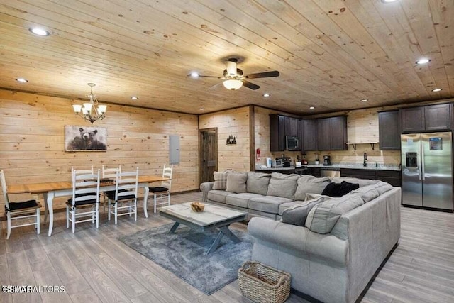 living room featuring wood walls, ceiling fan with notable chandelier, wooden ceiling, and light hardwood / wood-style flooring