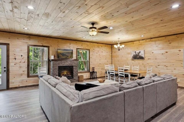 living room with a stone fireplace, ceiling fan with notable chandelier, wooden ceiling, and light hardwood / wood-style floors