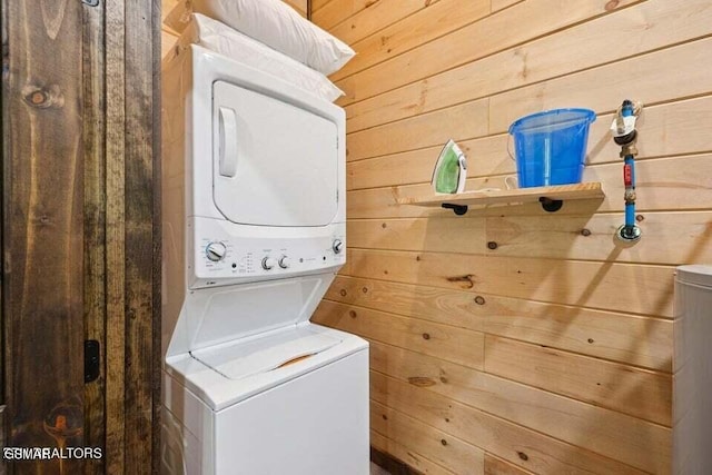 laundry area with stacked washer / dryer and wood walls