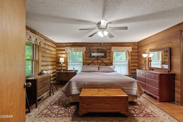 3114 Hatcher Top Rd, Sevierville, TN 37862 - bedroom featuring log walls, a textured ceiling, multiple windows, wood finished floors, and ceiling fan