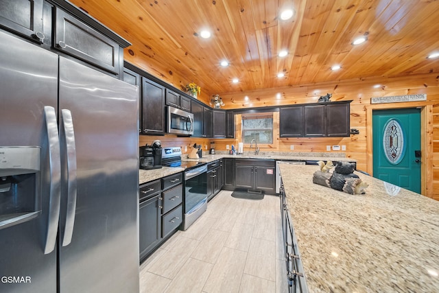 kitchen with light stone countertops, appliances with stainless steel finishes, wood ceiling, wooden walls, and sink