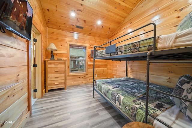 bedroom with wooden walls, wooden ceiling, vaulted ceiling, and wood-type flooring