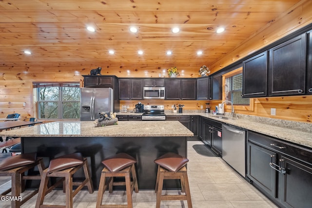 kitchen with a kitchen breakfast bar, light stone countertops, a center island, and appliances with stainless steel finishes