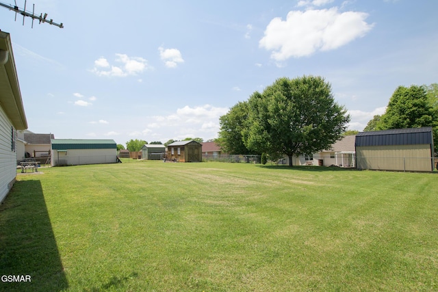 view of yard featuring fence, an outdoor structure, and a shed