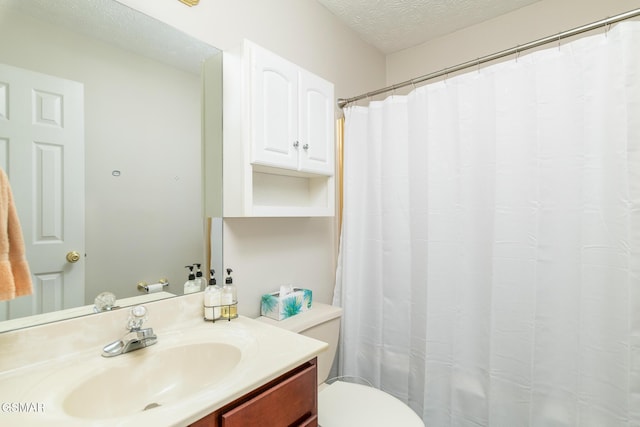 full bath with vanity, toilet, and a textured ceiling