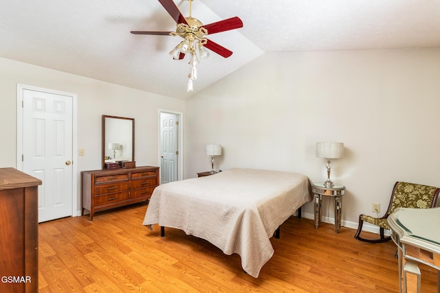 bedroom featuring baseboards, a ceiling fan, light wood-style flooring, and lofted ceiling