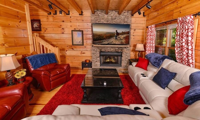 living room with a stone fireplace, beamed ceiling, wooden ceiling, and track lighting