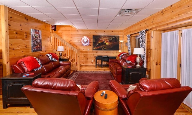 living room with hardwood / wood-style floors, a wood stove, and wooden walls