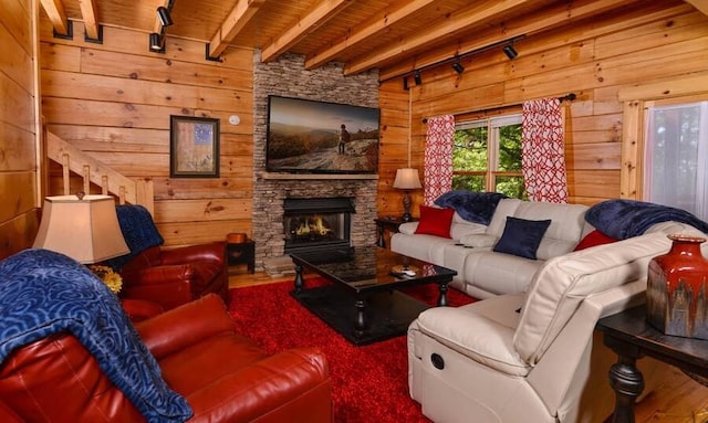 living room featuring wood walls, track lighting, a fireplace, beam ceiling, and wood ceiling