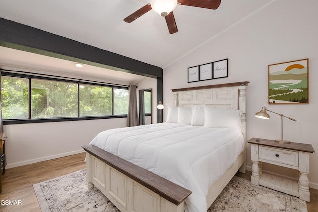 bedroom with light wood-type flooring, a ceiling fan, vaulted ceiling, and baseboards