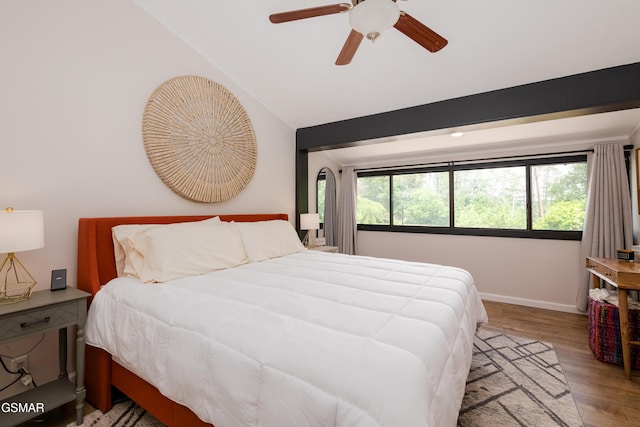 bedroom featuring baseboards, wood finished floors, a ceiling fan, and vaulted ceiling