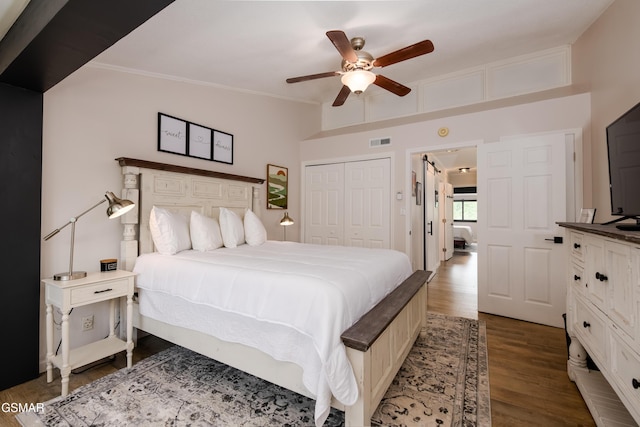 bedroom with crown molding, visible vents, ceiling fan, a closet, and wood finished floors
