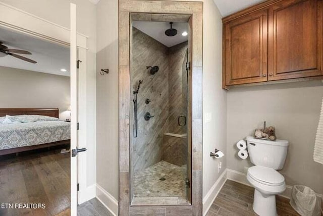 bathroom featuring toilet, a shower with door, and ceiling fan