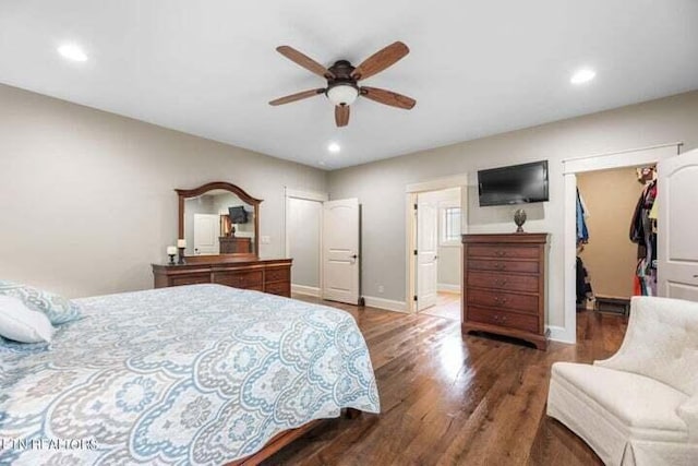 bedroom with dark wood-type flooring, ceiling fan, a spacious closet, and connected bathroom