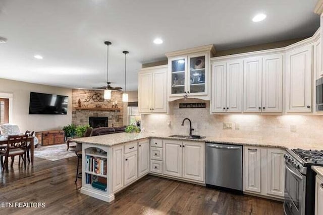 kitchen featuring sink, kitchen peninsula, dark hardwood / wood-style floors, pendant lighting, and appliances with stainless steel finishes