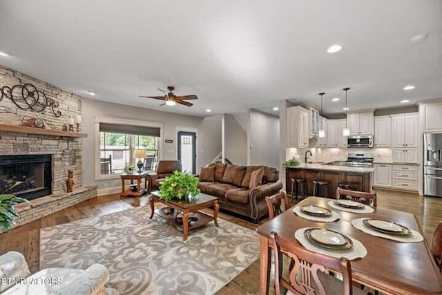 living room with sink, a fireplace, ceiling fan, and dark hardwood / wood-style floors