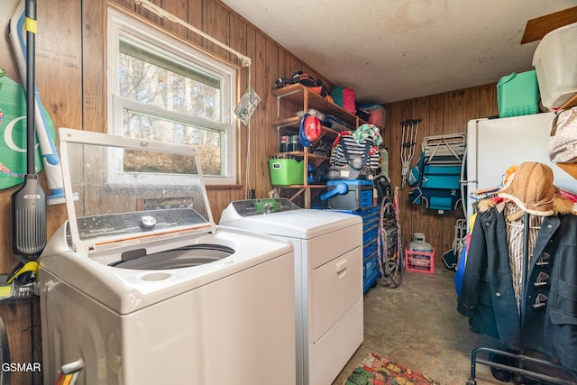 laundry area featuring washer and clothes dryer, wooden walls, and a textured ceiling