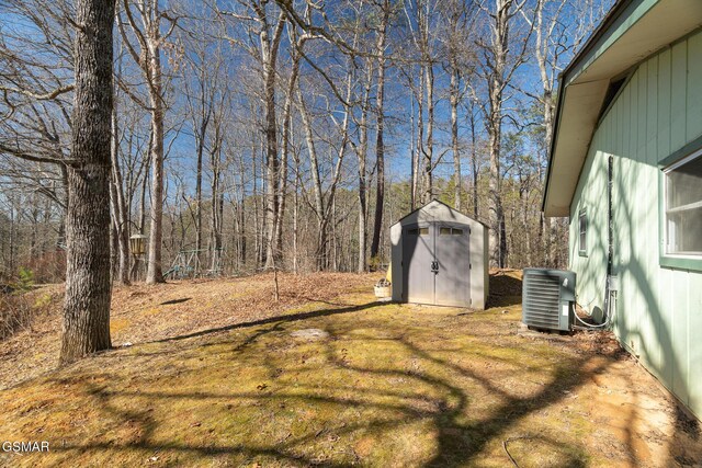 view of yard with central air condition unit and a storage unit