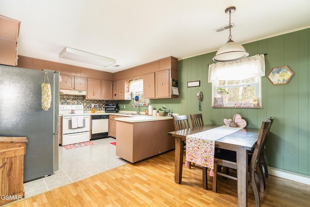 kitchen featuring tasteful backsplash, decorative light fixtures, light wood-type flooring, kitchen peninsula, and white appliances