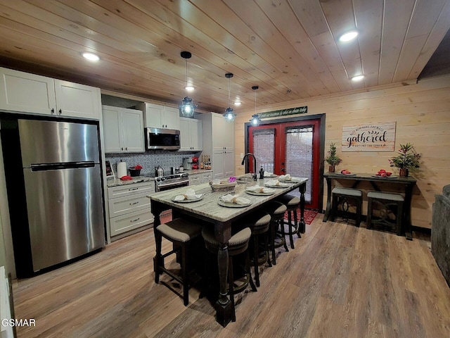 kitchen with light stone counters, wood ceiling, appliances with stainless steel finishes, and white cabinets