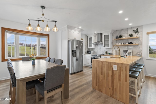 kitchen featuring stainless steel appliances, white cabinetry, kitchen peninsula, wood counters, and backsplash