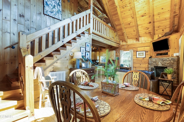 822 Eagle Cove Way, Gatlinburg, TN 37738 - dining space featuring wooden walls, high vaulted ceiling, a wooden ceiling with exposed beams, a stone fireplace, and wood-type flooring