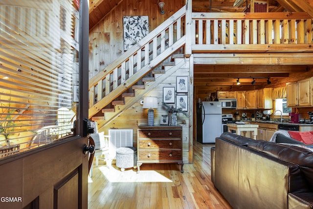 822 Eagle Cove Way, Gatlinburg, TN 37738 - kitchen with stainless steel appliances, wood walls, light wood-type flooring, dark countertops, and rail lighting