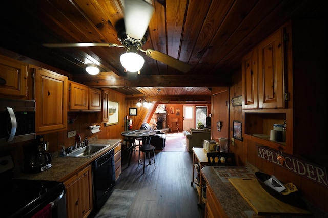 kitchen featuring ceiling fan, wooden walls, sink, black appliances, and beam ceiling